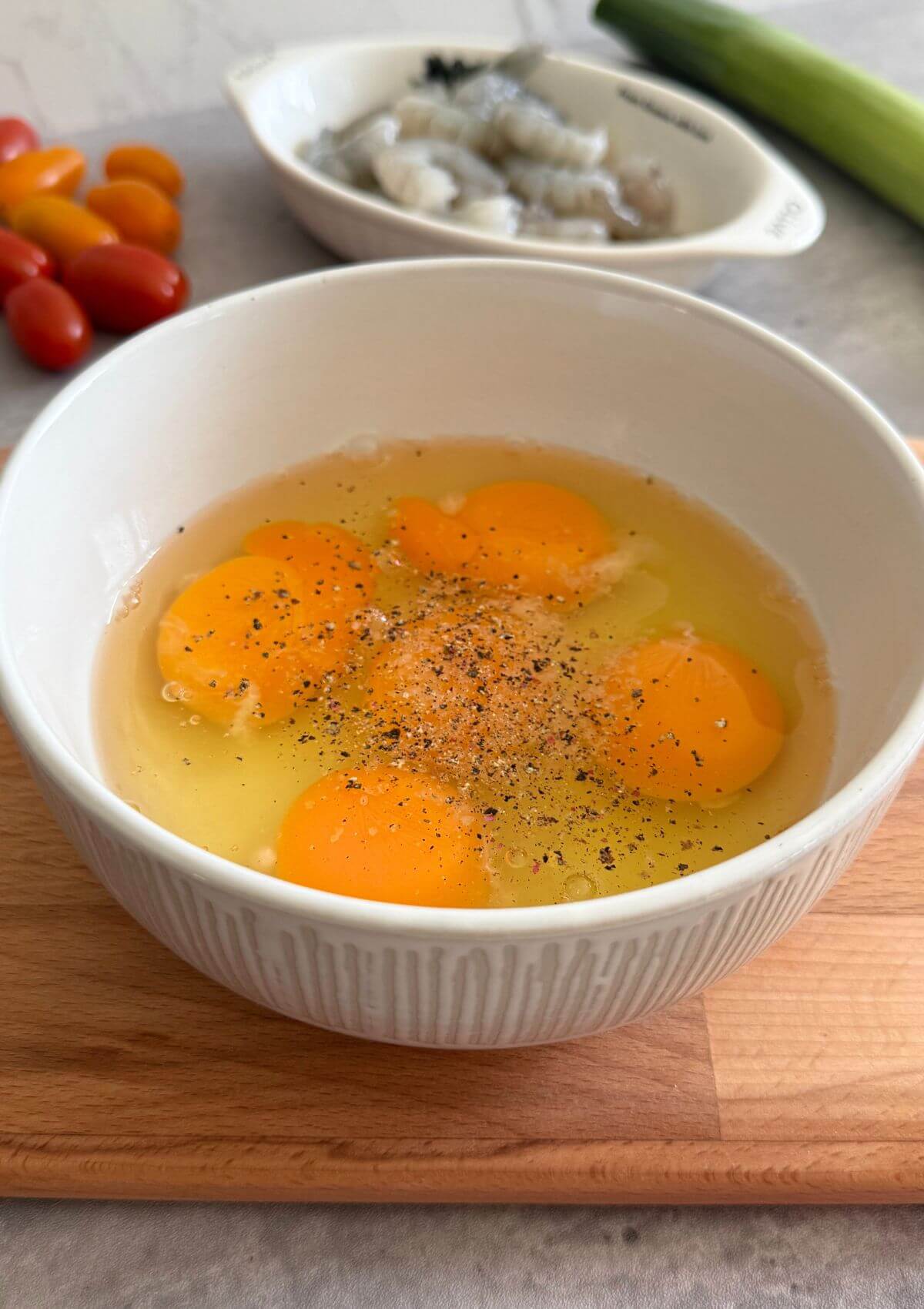 Hand cracking eggs into a bowl for shrimp leek frittata.