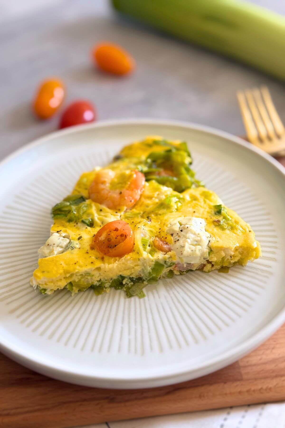 A slice of shrimp and leek frittata on a plate, showing its creamy texture and golden top.