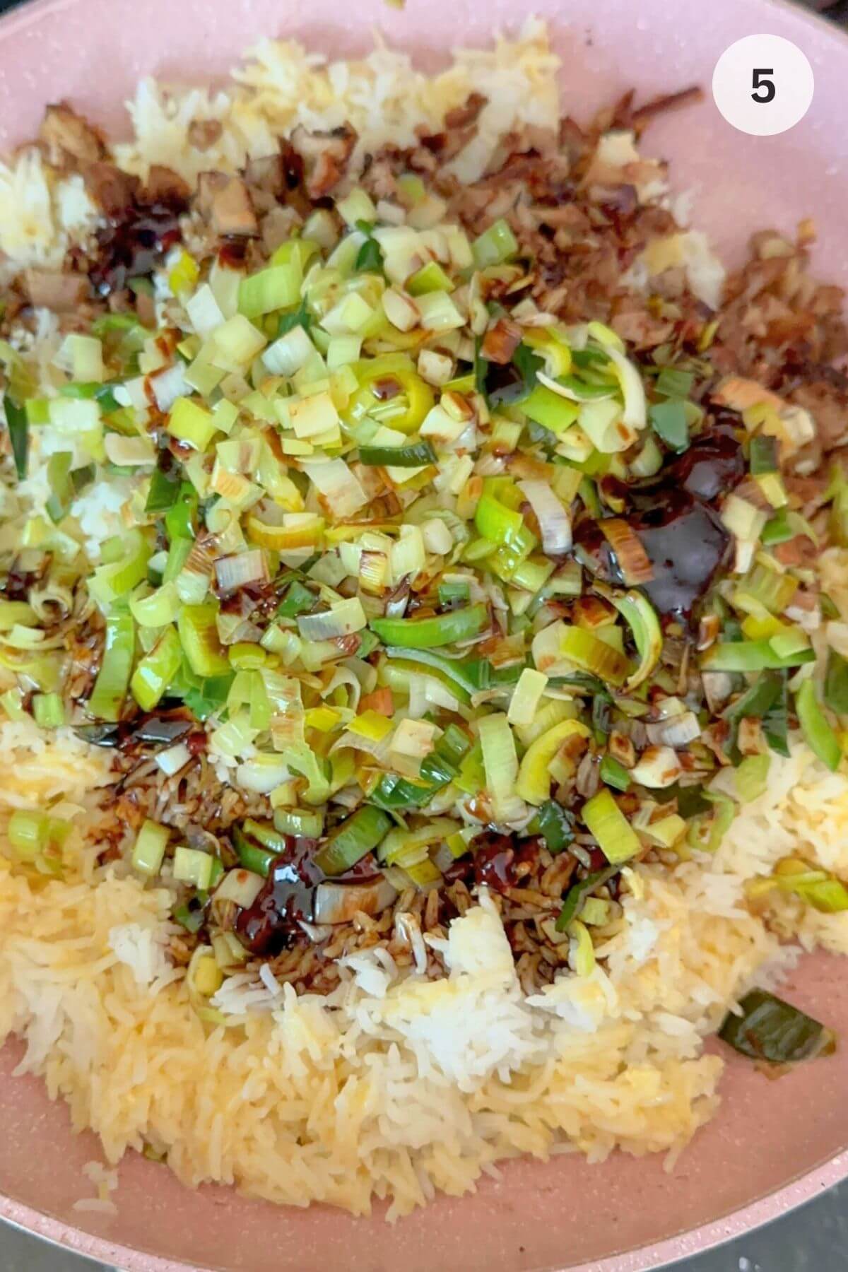 Fried rice coated in glossy sauce, steaming in wok mixed with the leeks, browned leftover lamb. 