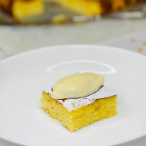 Alivenci slice on a plate topped with sour cream and powdered sugar.