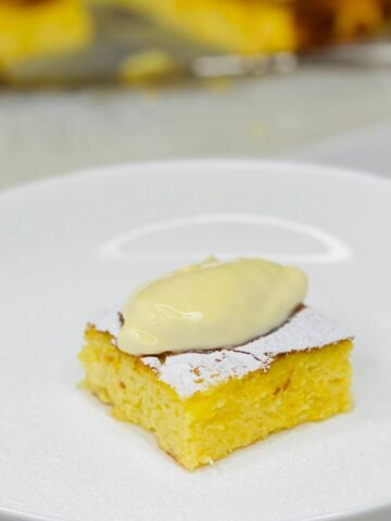 Alivenci slice on a plate topped with sour cream and powdered sugar.