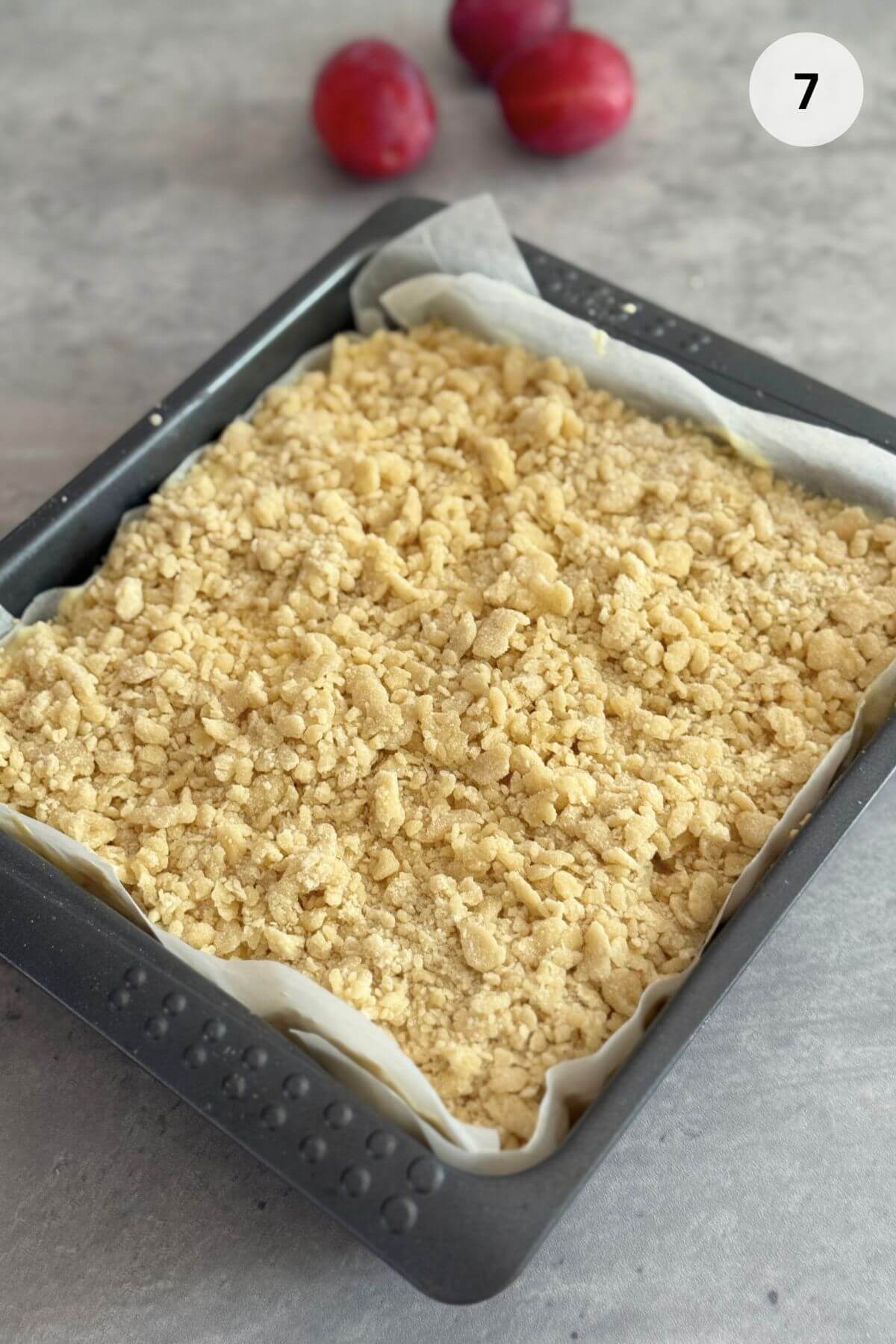 Small, coarse crumbs of raw dough scattered evenly across the surface of the creamy pudding layer.