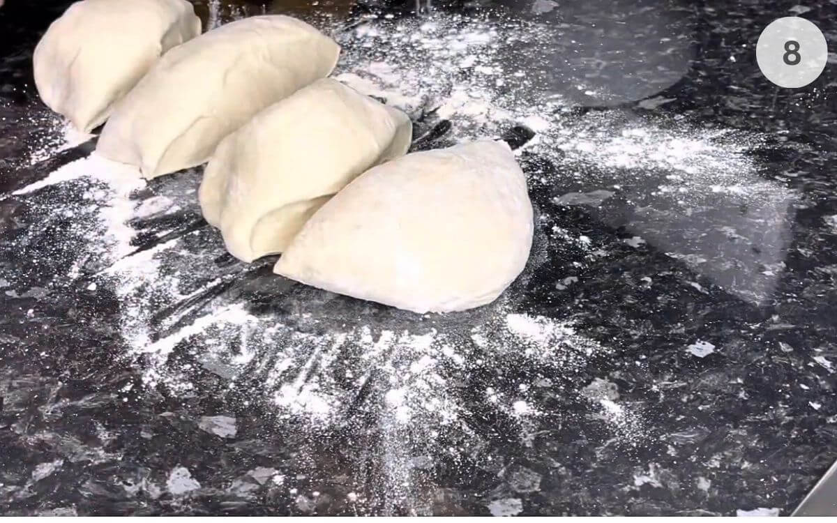 Dough divided into portions and rolled into smooth, round balls, ready for forming pizza bases.