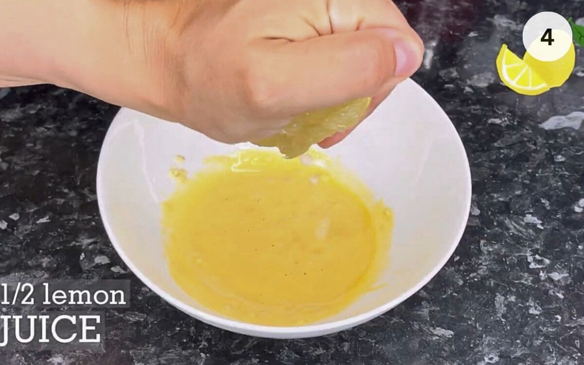 Whisking oil into egg yolks until mixture becomes thick and creamy.