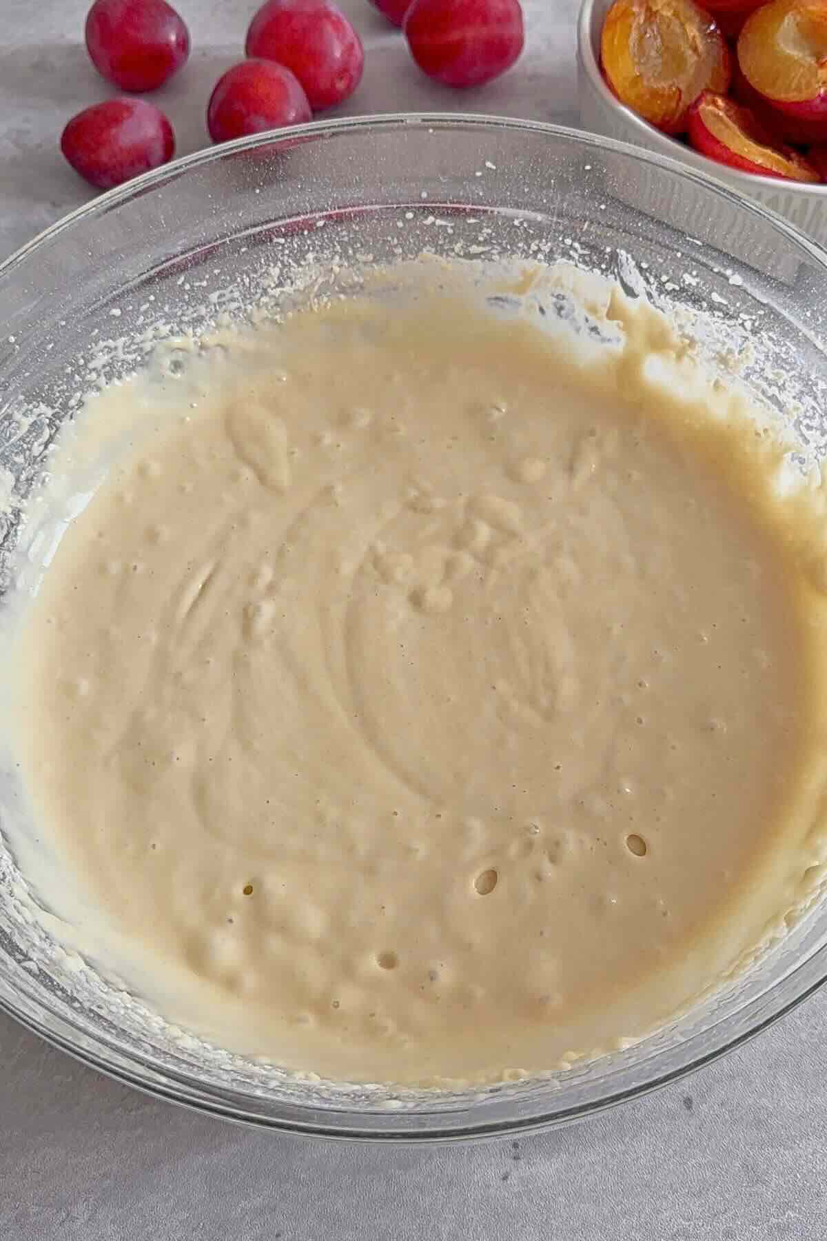 Smooth kefir plum cake batter in a bowl, ready to pour into the pan for baking.