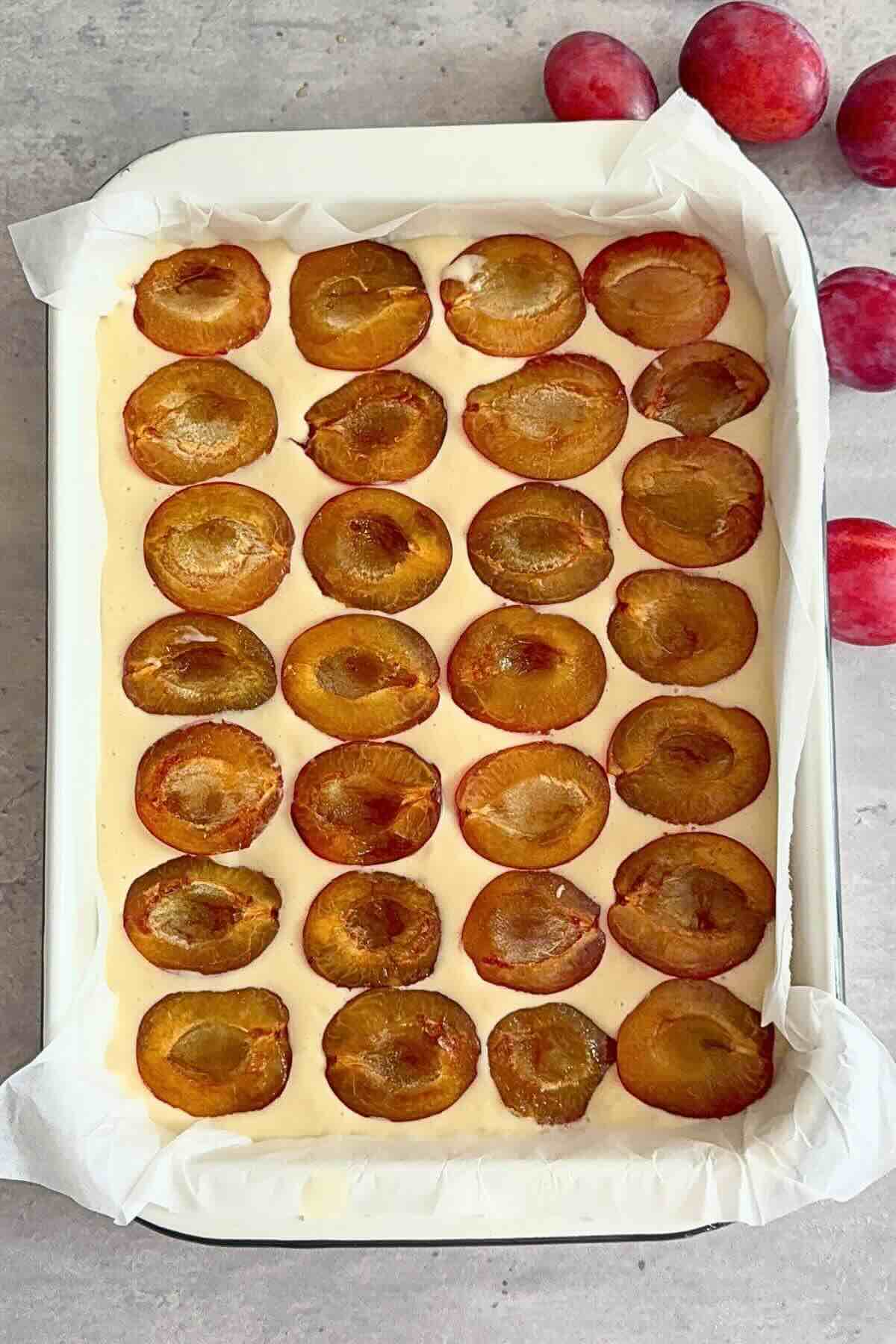 Fresh plum halves arranged cut-side up on top of the kefir cake batter before baking.