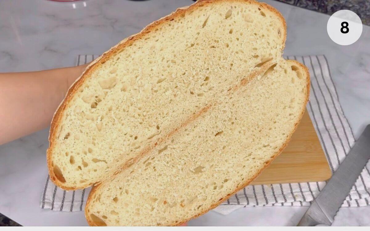 Romanian house bread sliced in half, showing soft, airy crumb inside.