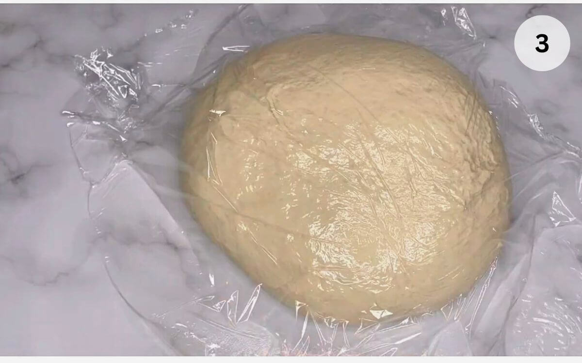 Stretching and folding the Romanian bread dough on an oiled surface during the first rise.