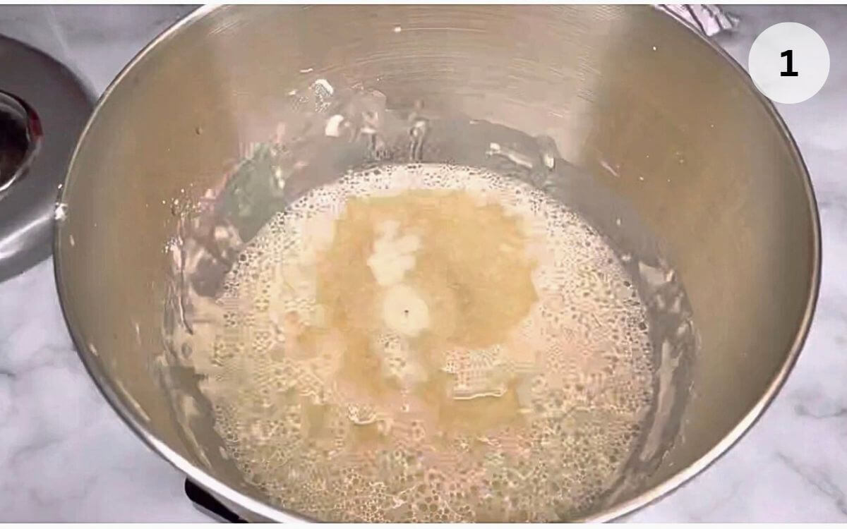 Mixing warm water, yeast, and flour in a large bowl to start Romanian house bread dough.