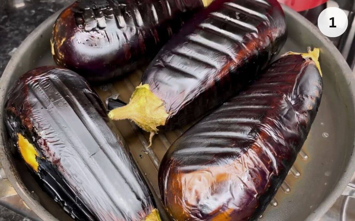 Eggplant being charred in a griddle pan until blackened and soft inside.