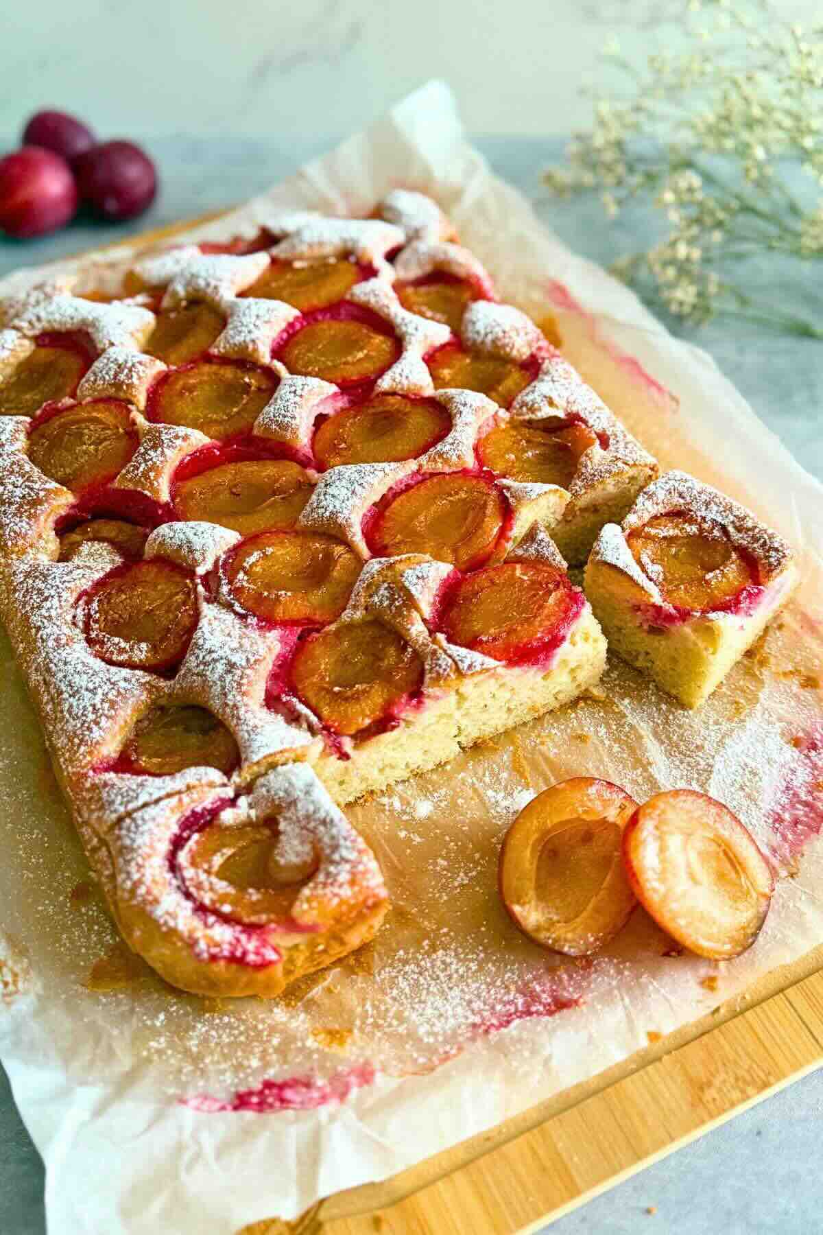 Slice of moist kefir plum cake, dusted with powdered sugar and ready to eat.