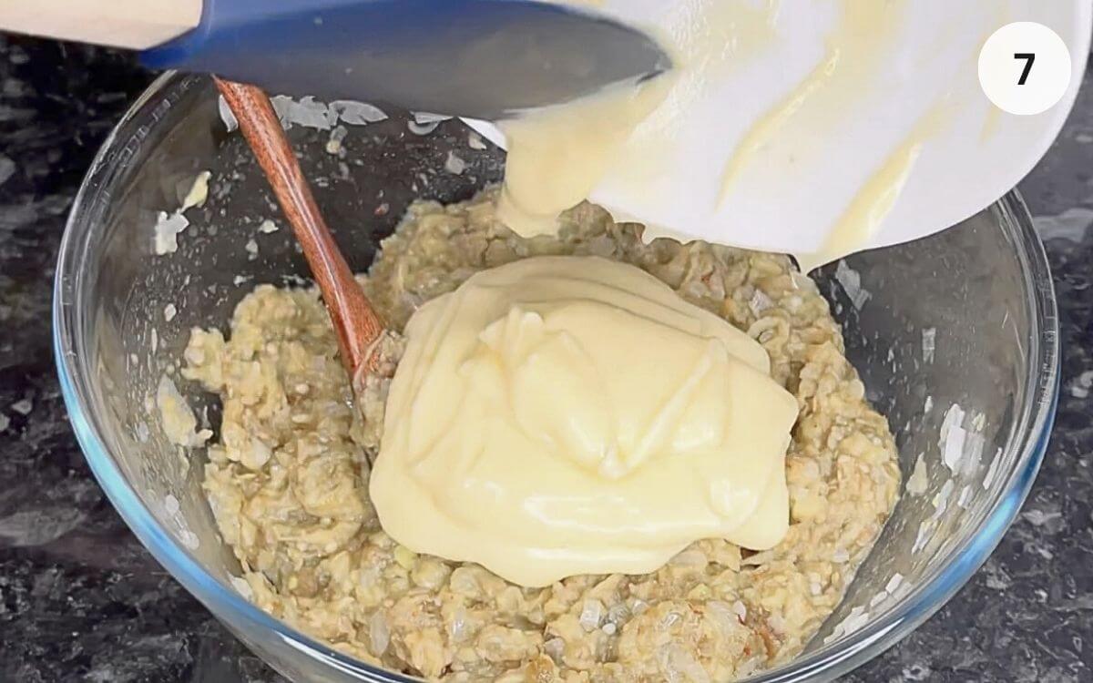 Chilled mayonnaise being added into the eggplant mixture.