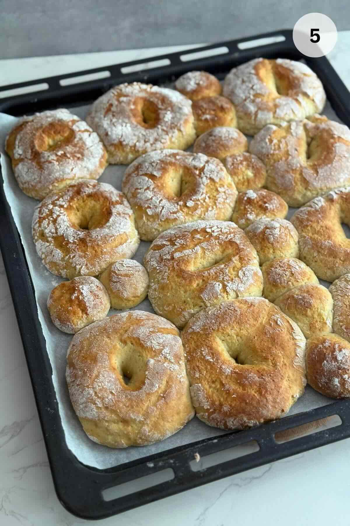 Baked papanasi pastries puffed and golden brown on a baking sheet.