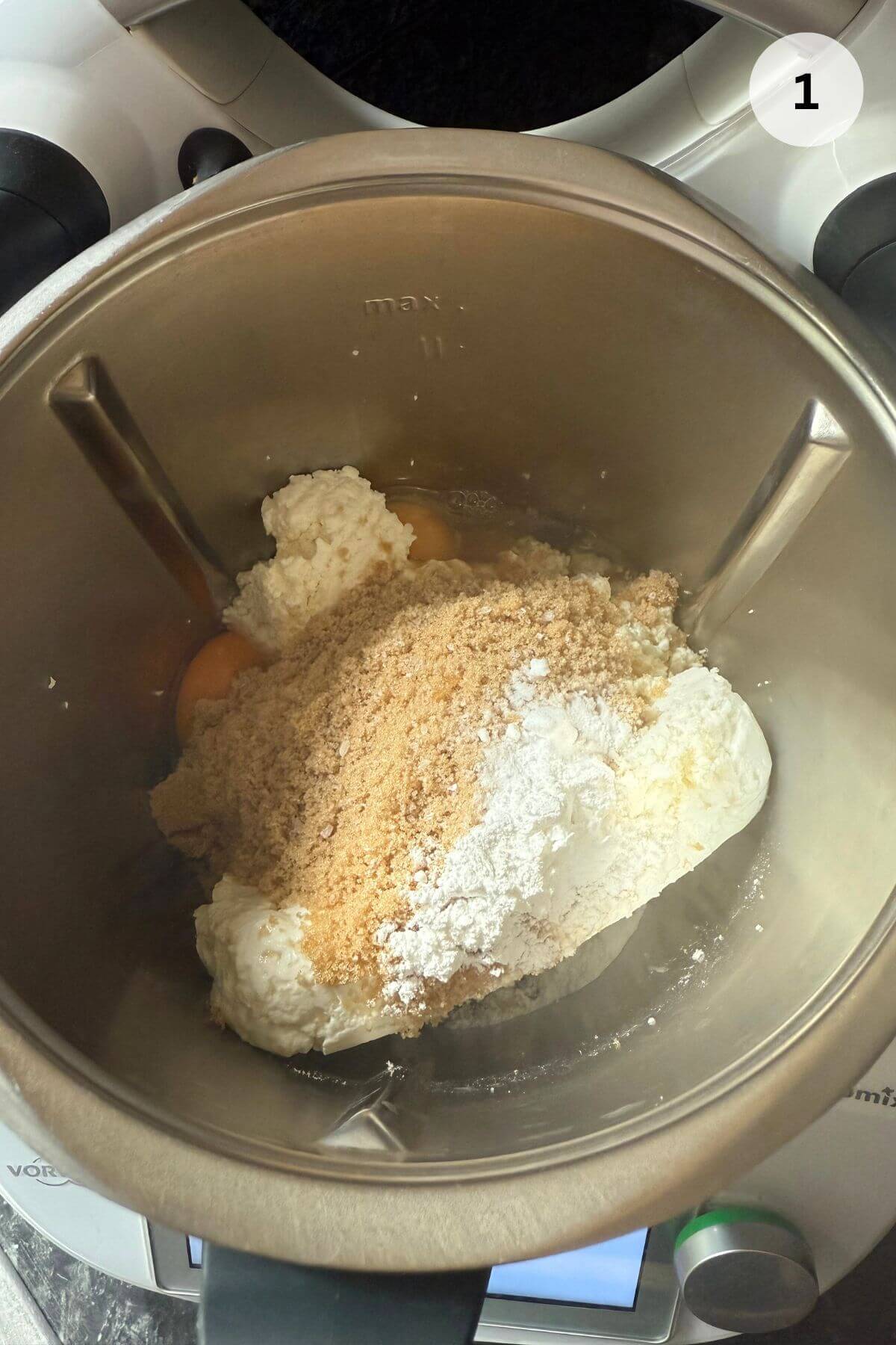 Mixer bowl with cottage cheese, eggs, sugar, and salt being mixed for baked papanasi.