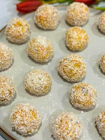 Vibrant carrot cake energy balls, rolled in coconut for a soft, chewy bite.
