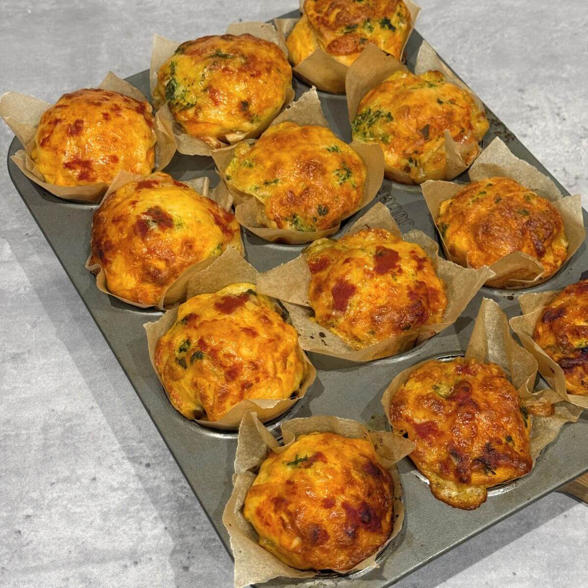 Garlic butter pizza cupcakes cooling, baked golden and topped with melted cheese.