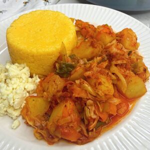 A plate of finished Romanian cabbage potato stew with polenta and cheese.