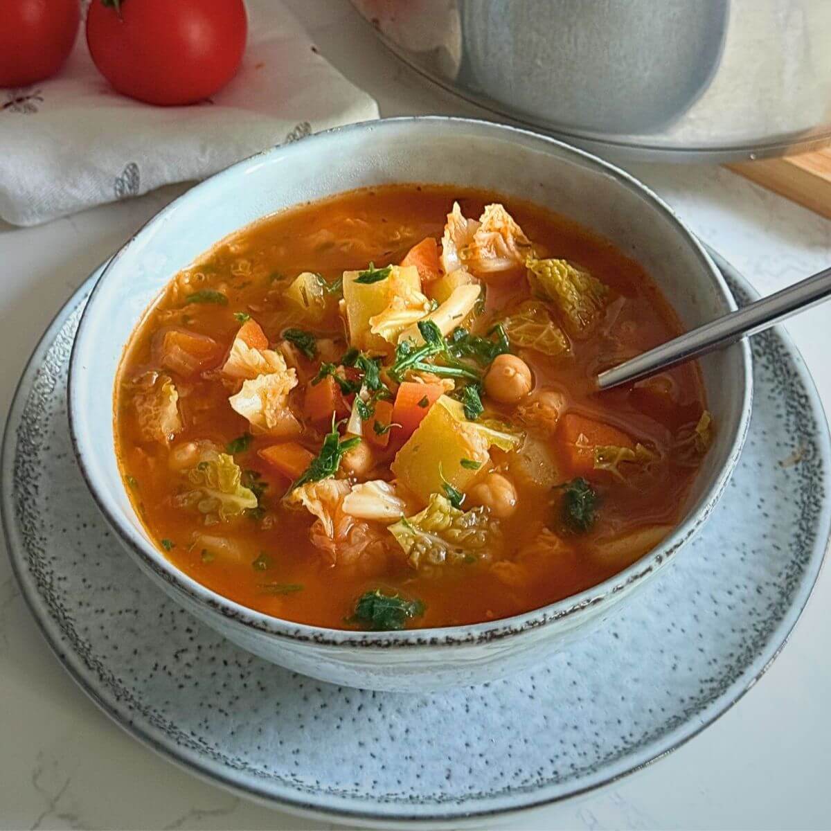 A steaming bowl of hearty cabbage potato soup with carrots and chickpeas.