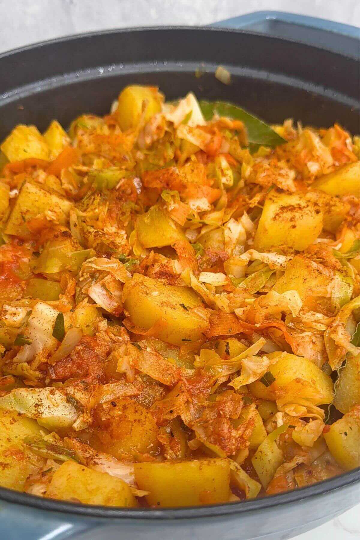 Hearty Romanian cabbage and potato stew with tomato sauce and herbs.