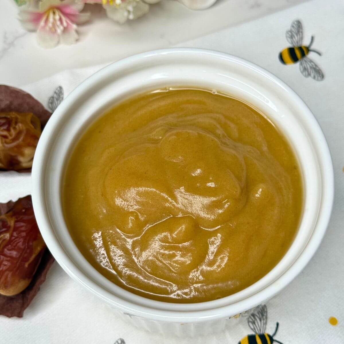 Creamy coconut milk date caramel sauce in a white ceramic dish, perfect for desserts or dipping.