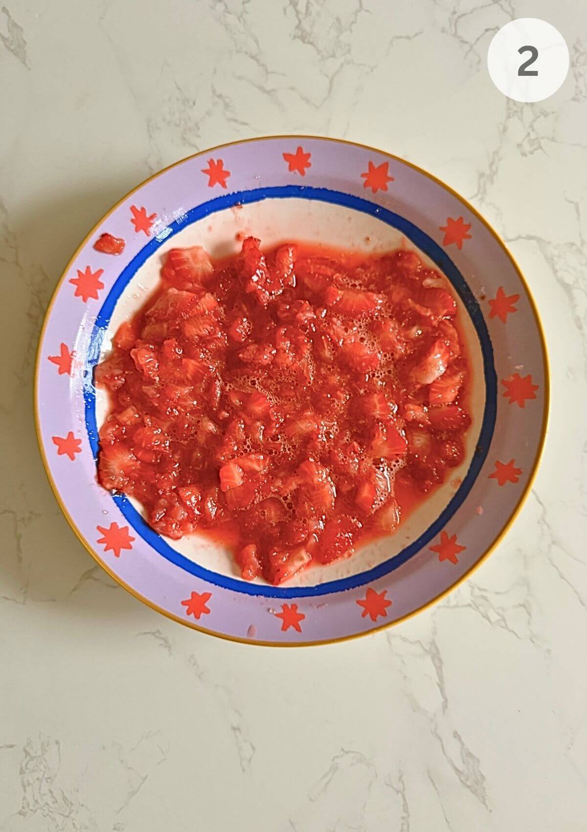 Strawberries being lightly crushed with brown sugar using a fork.