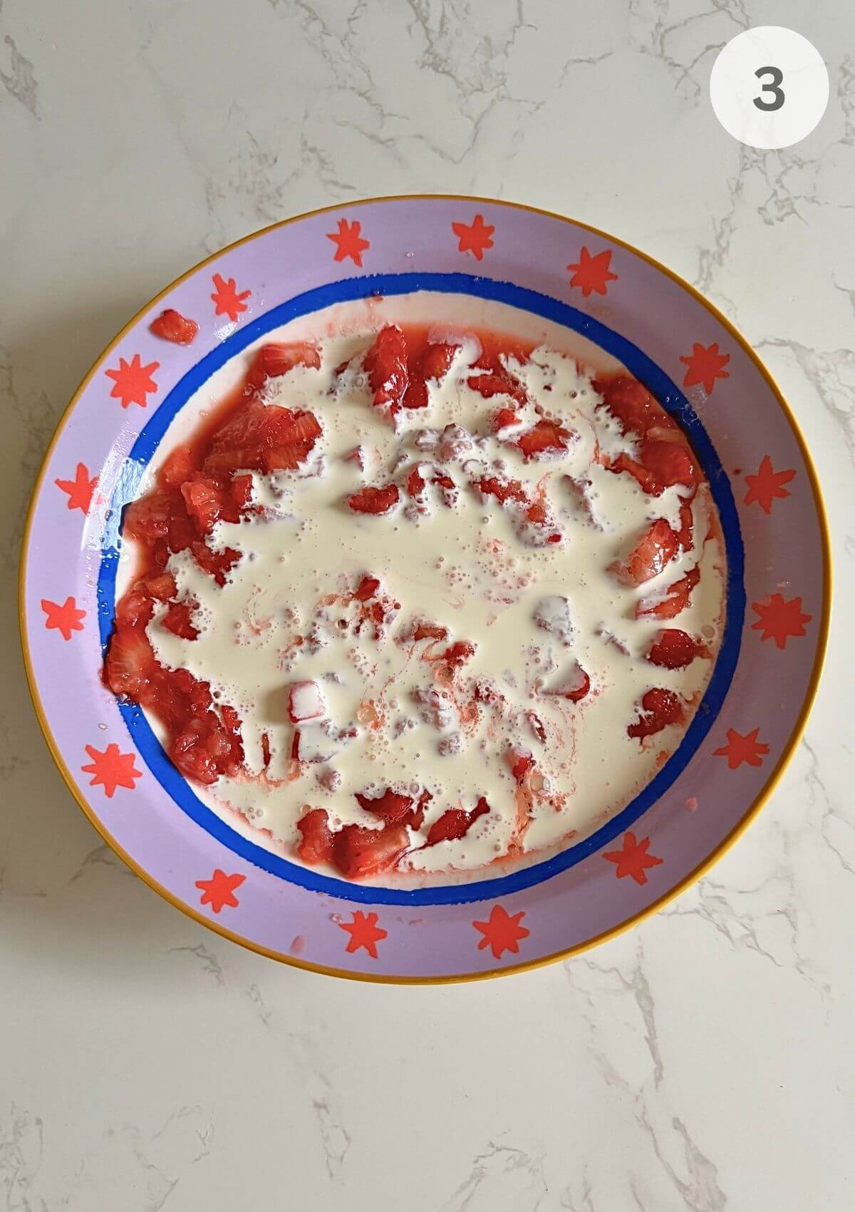 Heavy cream being poured over the crushed strawberries.