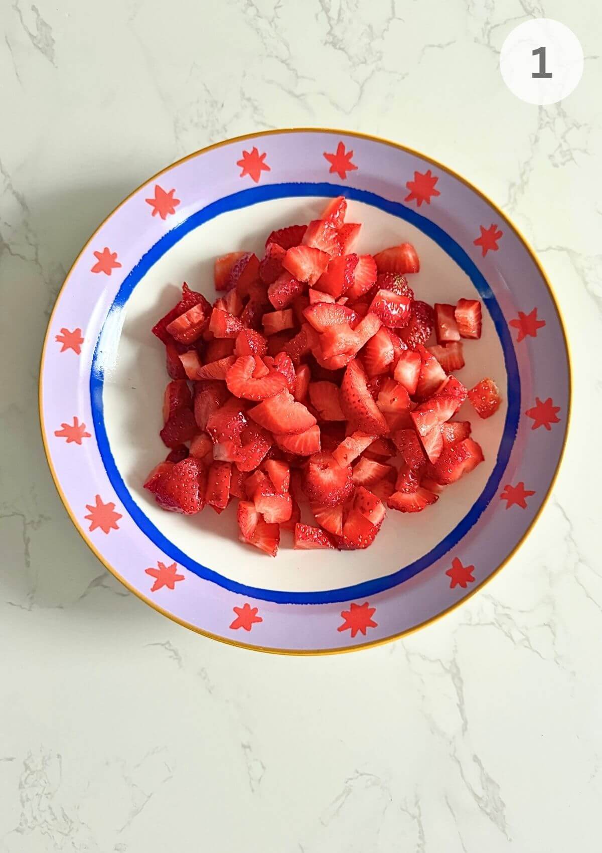 Washed and chopped strawberries in a bowl, ready to be crushed.