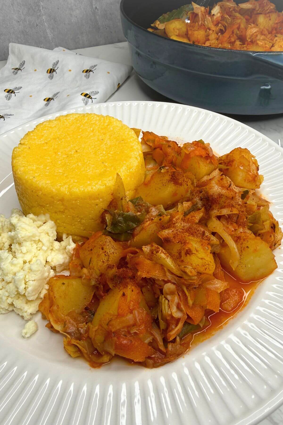 A plate of finished Romanian cabbage potato stew with polenta and cheese.