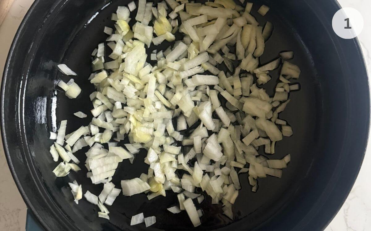 Onions sautéing in oil until soft and translucent in a shallow pan.