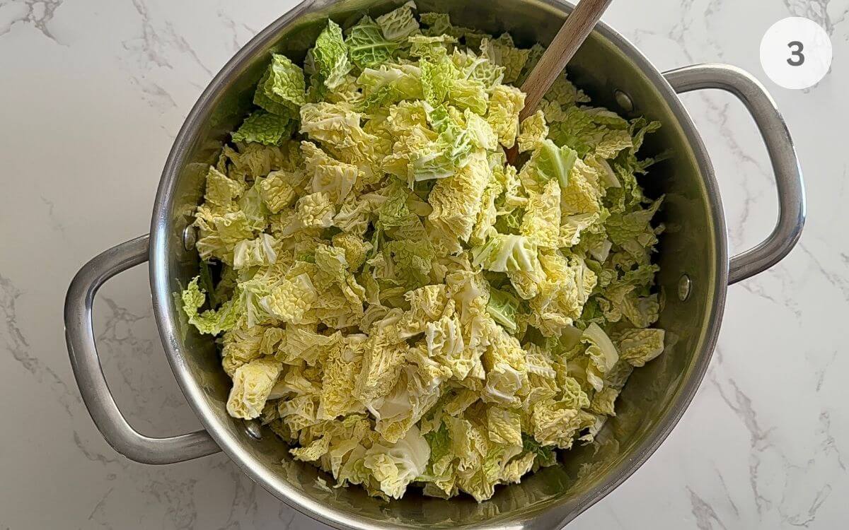 Cabbage cut in half, core removed, sliced into strips, and chopped into small squares, added in the pot.
