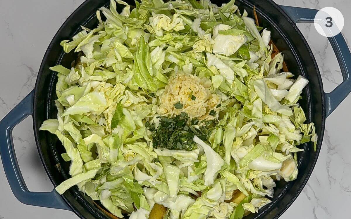 Cabbage and crushed garlic added to the pan, mixed with other vegetables.