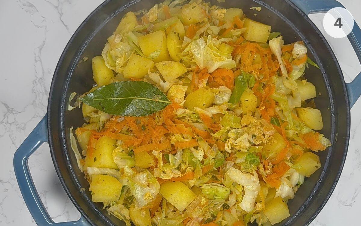 Water, rosemary, and bay leaves poured over vegetables, pan covered to simmer.