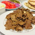 Slices of spiced, oven-baked viral doner kebab meat served in a warm pita with lettuce, tomatoes, and garlic yogurt sauce.