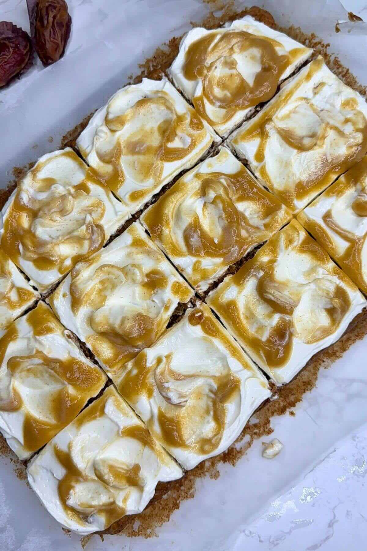 Overhead view of a whole apple cake with creamy frosting on a marble slab.