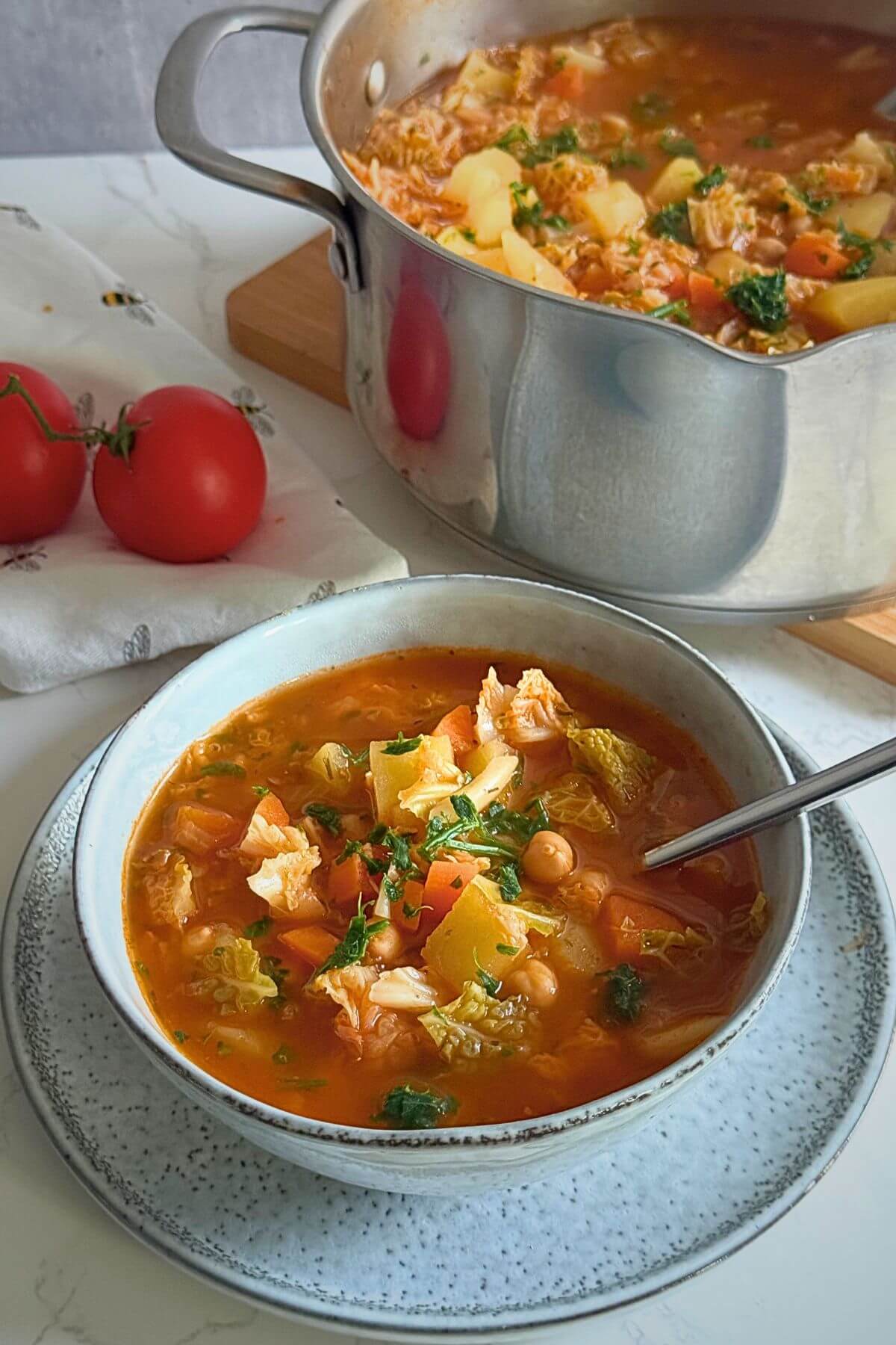 A steaming bowl of hearty cabbage potato soup with carrots and chickpeas.
