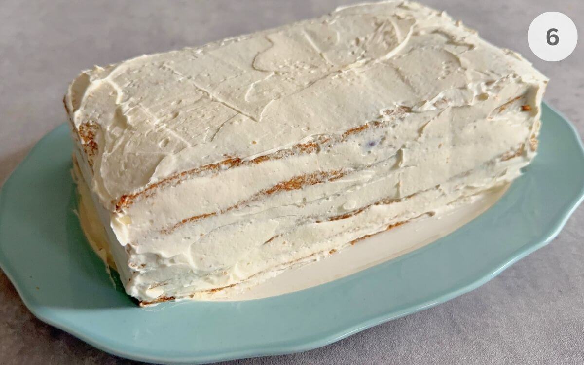 The stacked six layer honey cake completely covered in smooth white mascarpone cream frosting.