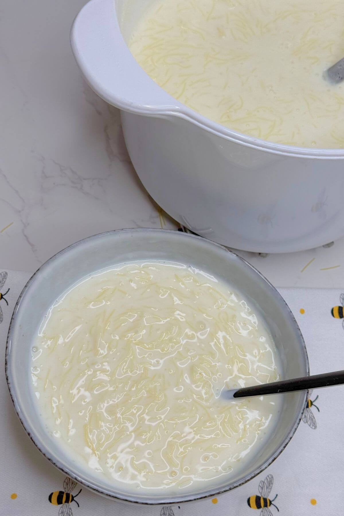 Pan and serving bowl filled with sweet vermicelli pudding set aside cooling.