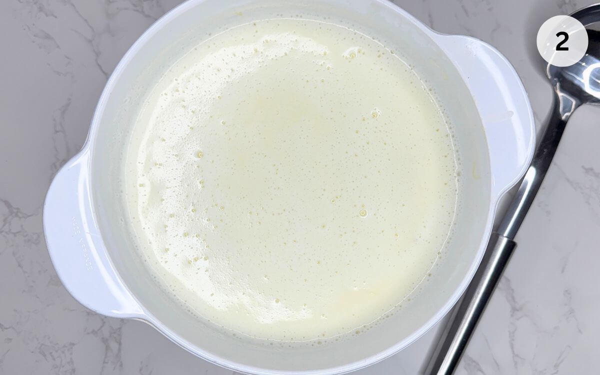 Vermicelli pasta stirred into simmering milk in pan, cooking until tender for Romanian dessert.