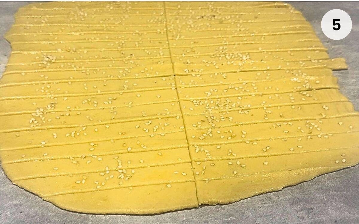 Dough cut into strips, brushed with egg, and topped with seeds.