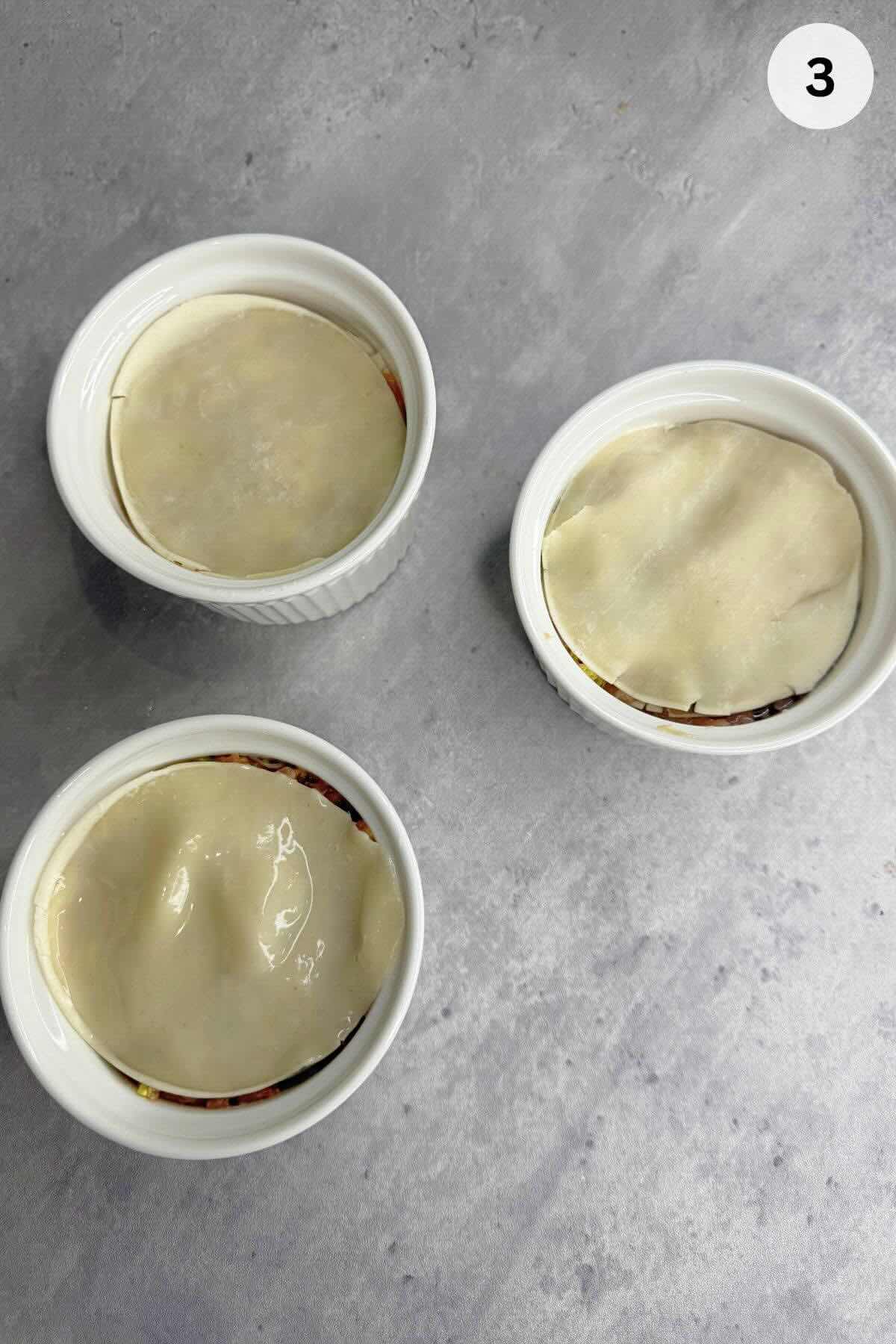 Meat mixture spooned into ramekin, pressed flat, and topped with dumpling wrapper for first layer.