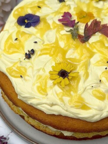 Three Layer Lemon Cake decorated with lemon cream cheese frosting, lemon curd swirls and edible flowers.