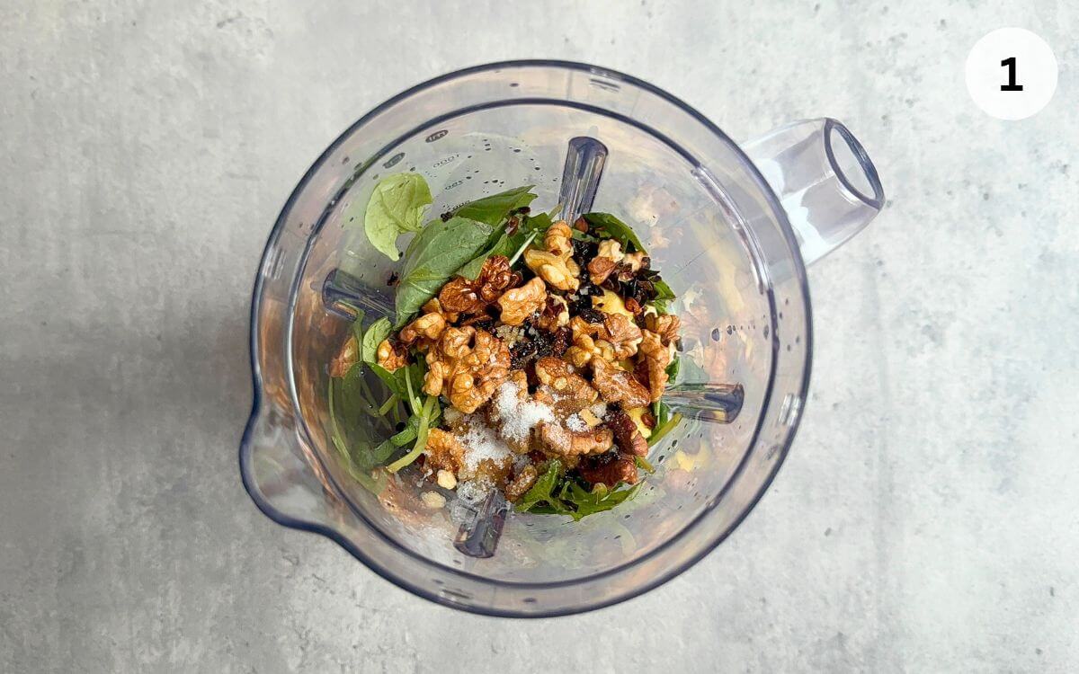 Chopped garlic, ginger, walnuts, Thai basil, and chili in a food processor ready to blend.