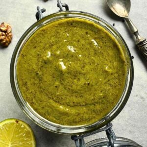 Thai basil pesto in jar with fresh basil and lime.