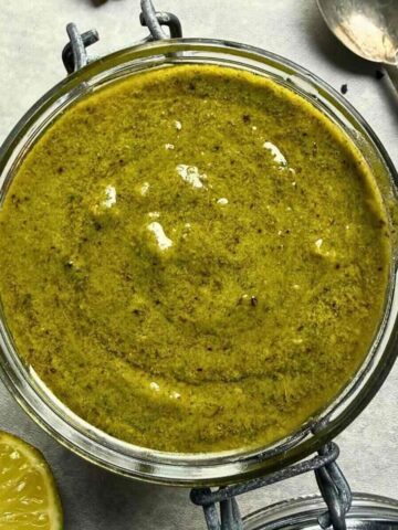 Thai basil pesto in jar with fresh basil and lime.