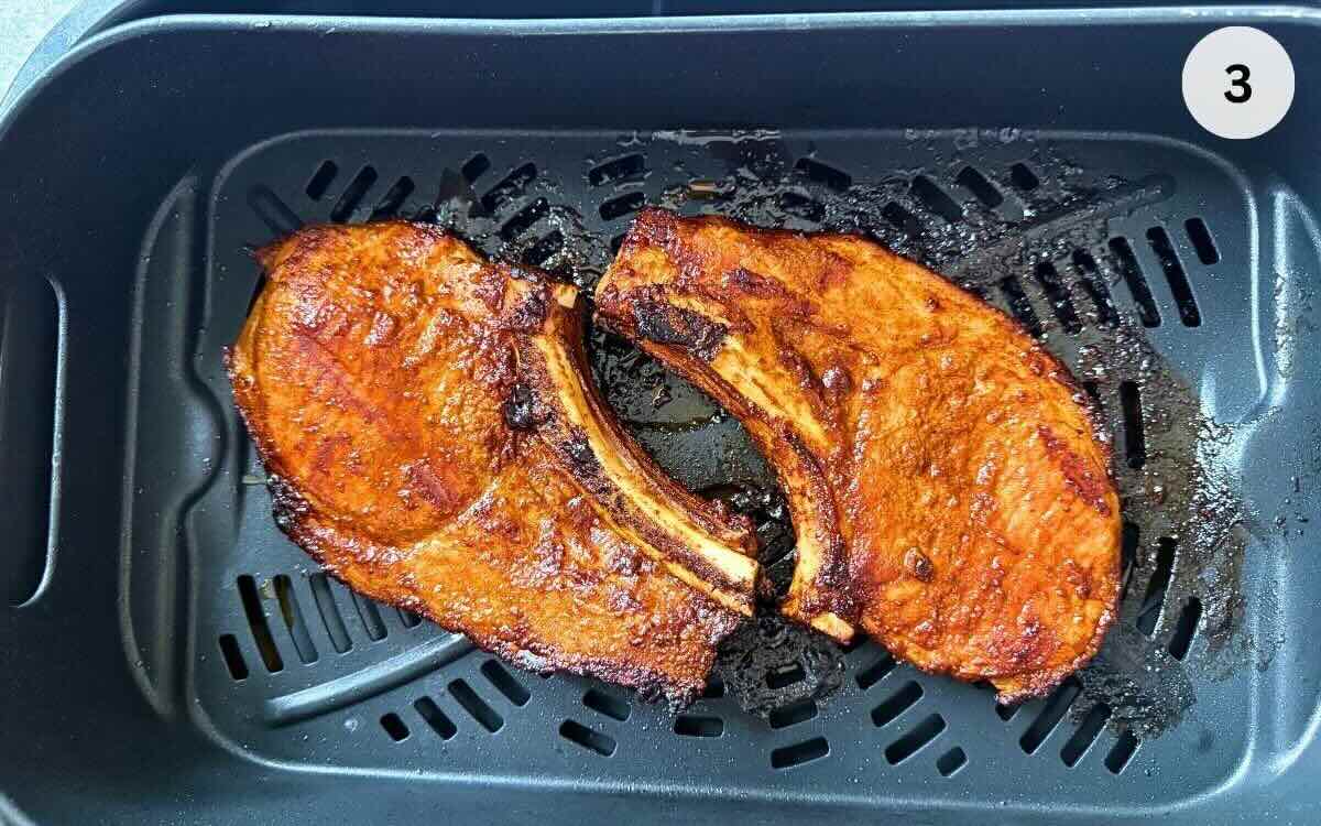 Thick pork chops cooking in air fryer basket at 400°F, flipped halfway through.