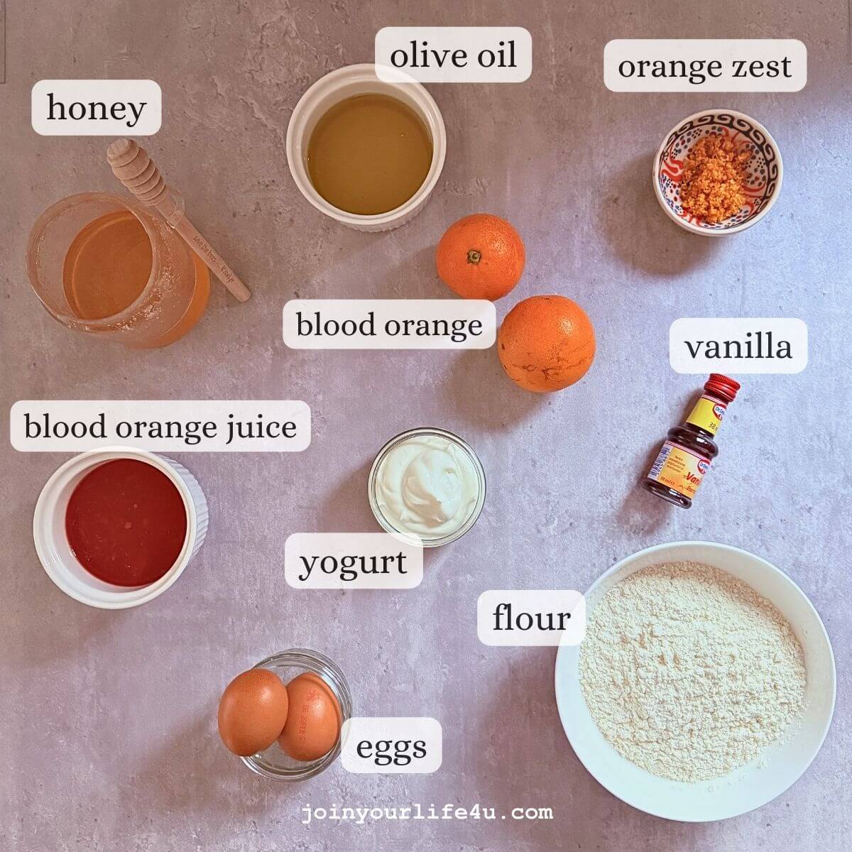 Oranges, eggs, olive oil, vanilla, Greek yogurt, honey, flour, cornmeal, individually displayed on a table.