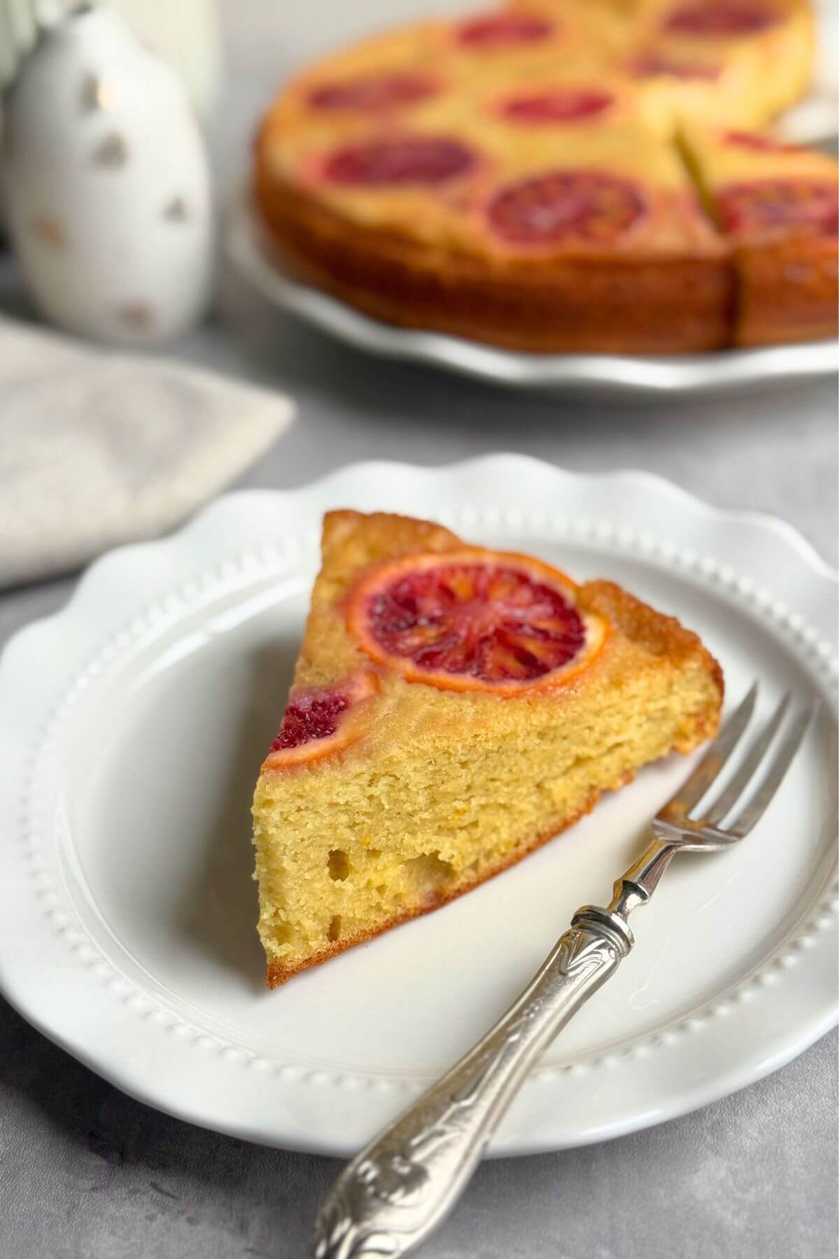 A slice of blood orange upside down cake on a white plate showing moist crumb.
