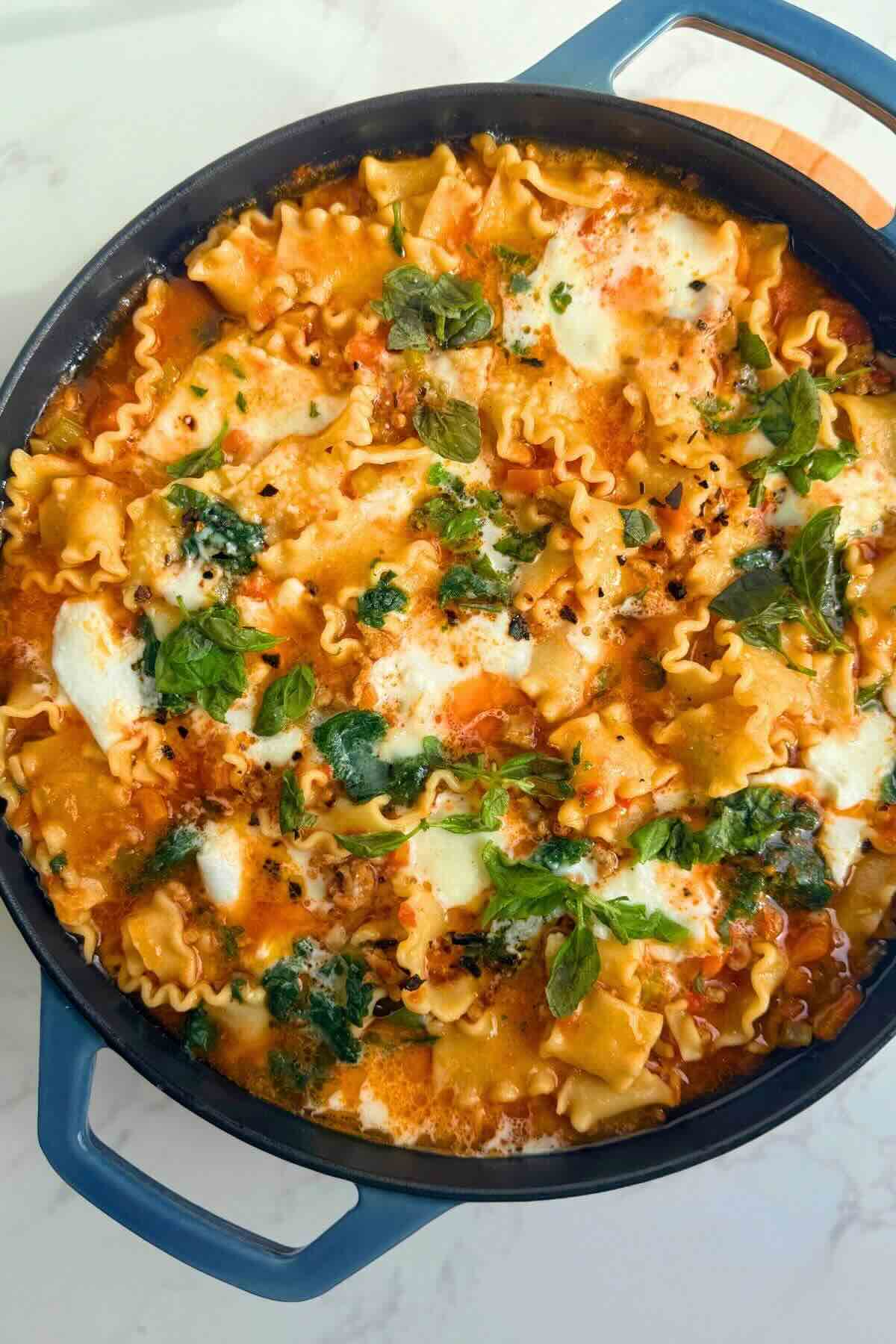 One-pan lazy lasagna with ricotta and fresh basil in a cast iron skillet.