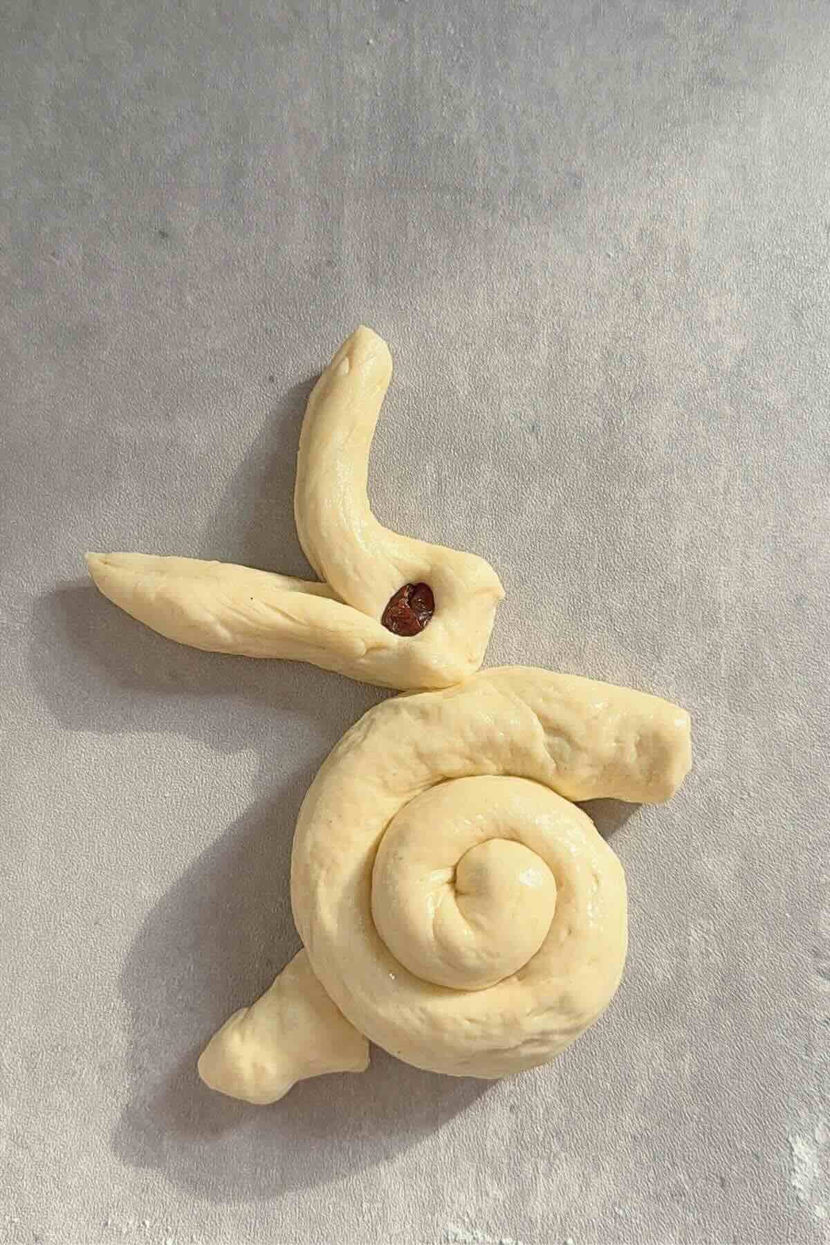 Bunny head shaped, ears split, raisin eye pressed into dough.