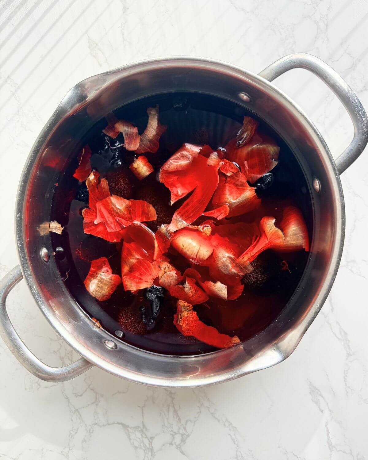 Large pot with red onion peels beetroot and wrapped eggs in natural red dye bath.